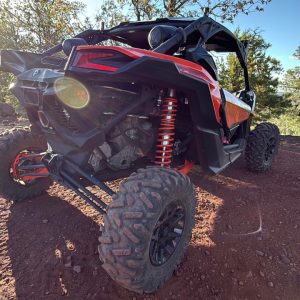 Close-up of Can-Am UTV tires and suspension on red-dirt trail
